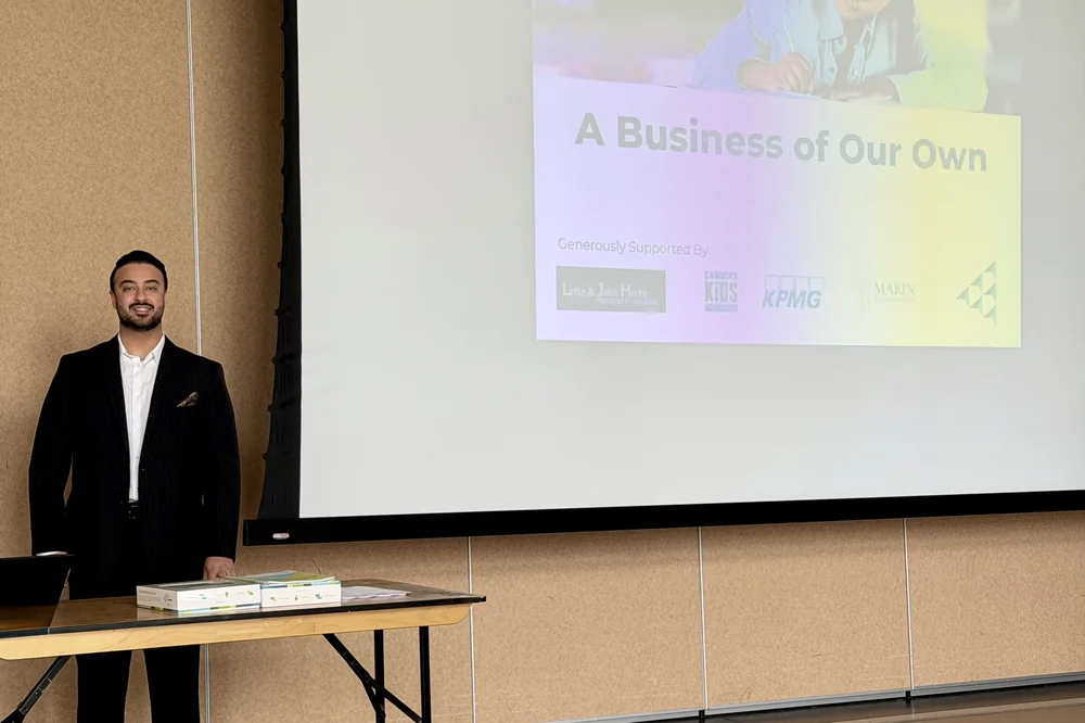 Ali Owji beside a projection screen reading “A Business of Our Own”.