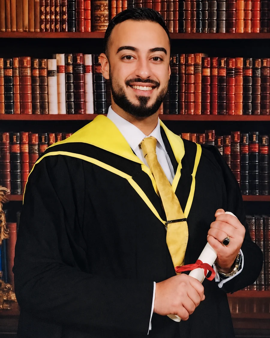Ali Owji in academic gown holding his degree scroll.